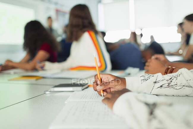High school student studying, writing in notebook during lesson in classroom — Stock Photo
