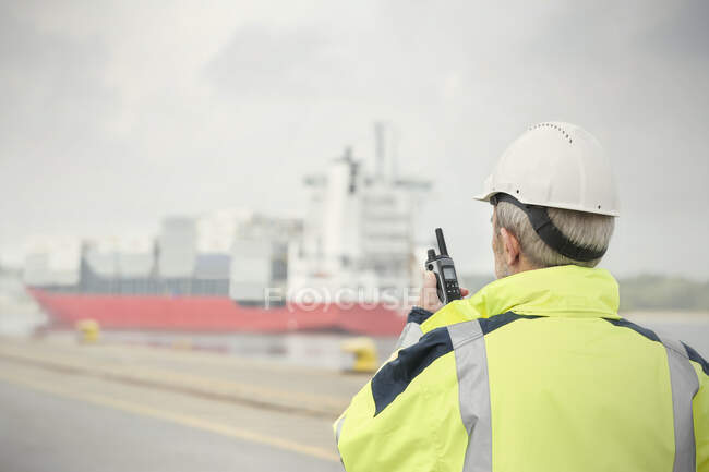 Gestionnaire de quai avec talkie-walkie regarder porte-conteneurs au quai commercial — Photo de stock