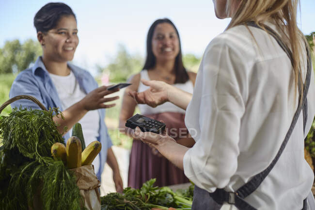 Жінка платить кредитною карткою на ринку фермерів — стокове фото