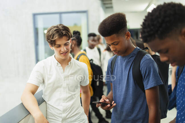 Junior high boy students using smart phone in corridor — Stock Photo