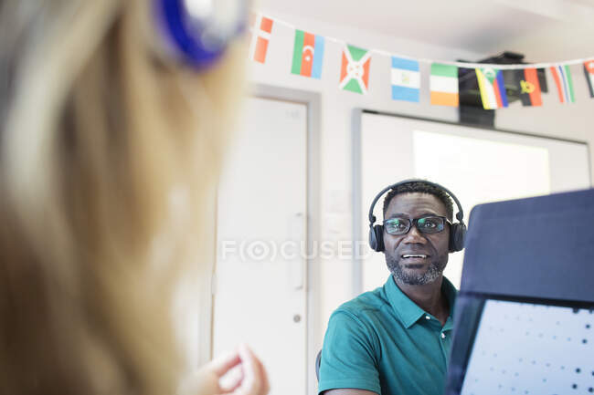 Mature male community college student with headphones using computer in classroom — Stock Photo