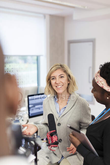 Smiling young female community college students at microphone in journalism class — Stock Photo