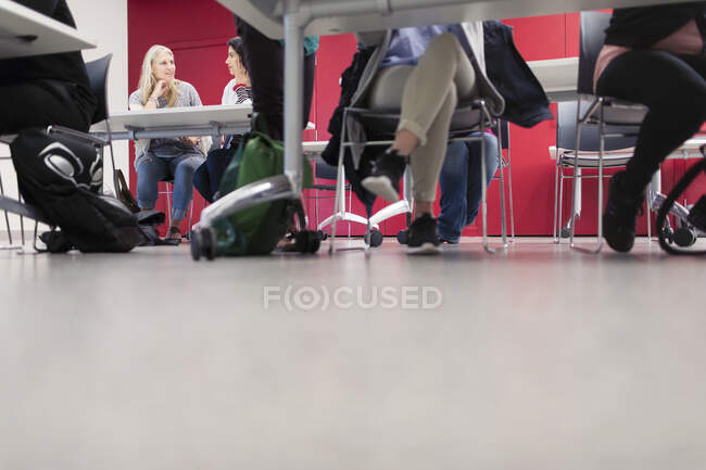 Pernas de estudantes universitários comunitários debaixo de mesas em sala de aula — Fotografia de Stock