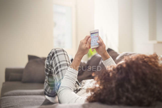 Чоловік розслабляється, використовуючи смартфон на дивані — стокове фото