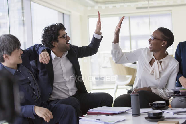 Gente de negocios chocando los cinco años en la sala de conferencias - foto de stock