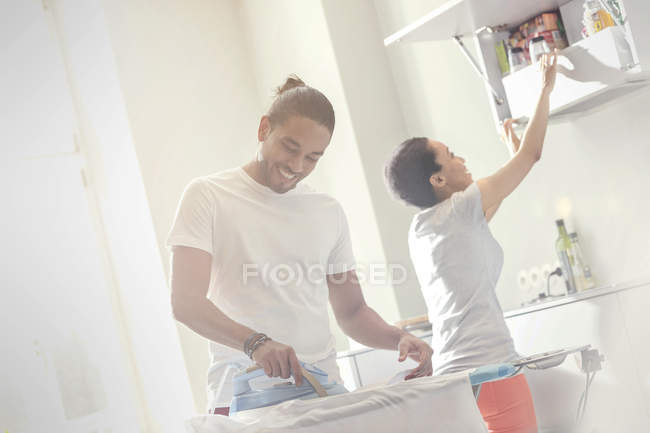 Paar wäscht, bügelt Wäsche in der Waschküche — Stockfoto