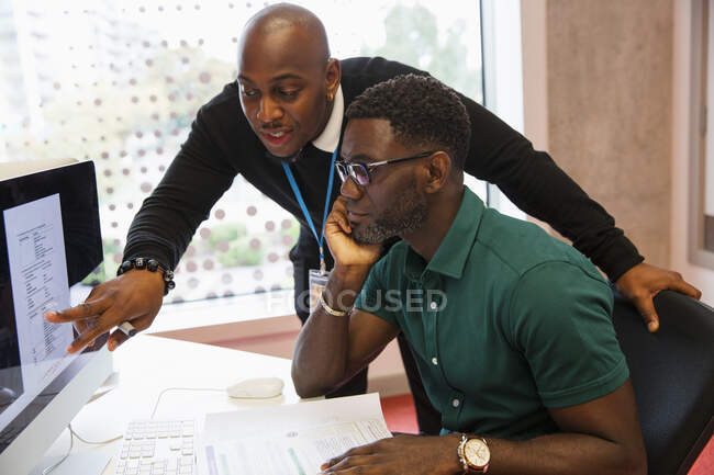 Instrutor universitário da comunidade masculina ajudando o estudante usando o computador no laboratório de informática — Fotografia de Stock