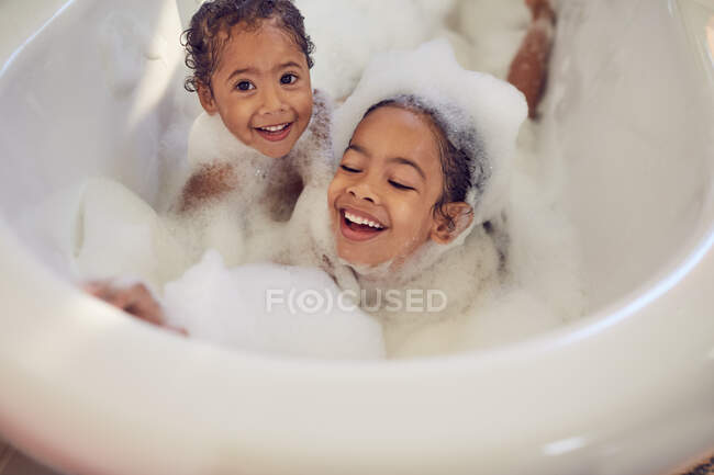 Ritratto giocoso sorelle godendo bagno bolla — Foto stock