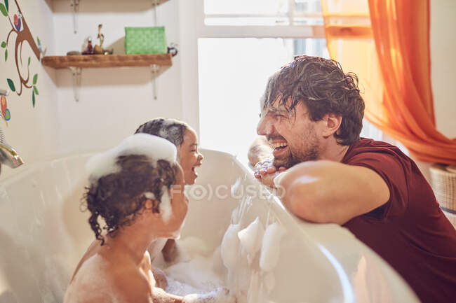 Грайливий батько дає маленьким донькам бульбашкову ванну — стокове фото