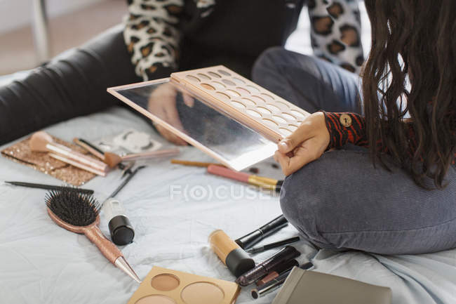 Teenage girls applying makeup on bed — Stock Photo