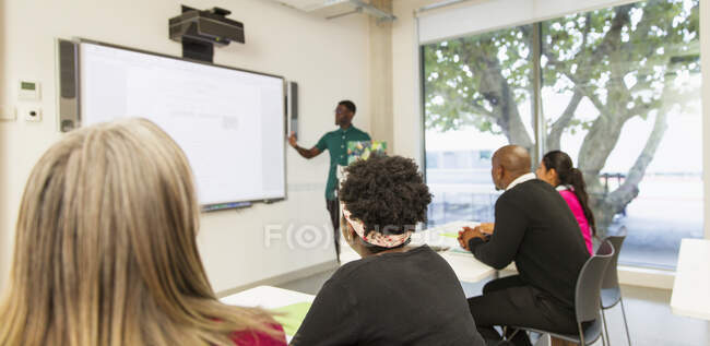Estudantes universitários comunitários assistindo instrutor lição de liderança na tela de projeção em sala de aula — Fotografia de Stock