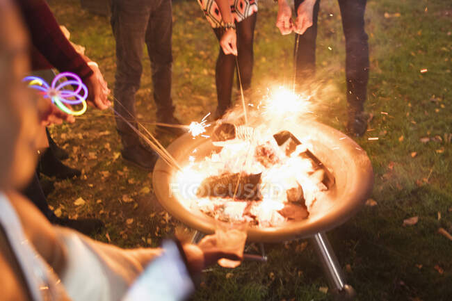 Friends lighting sparklers at fire pit — Stock Photo