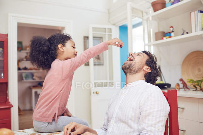 Cute daughter feeding father grape — Stock Photo