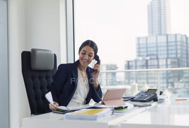 Усміхнена бізнес-жінка розмовляє по телефону в міському офісі. — стокове фото