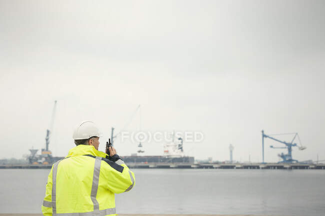 Trabajador portuario con walkie-talkie en muelle comercial - foto de stock