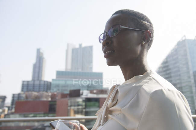 Femme d'affaires ambitieuse et confiante sur un balcon ensoleillé et urbain — Photo de stock
