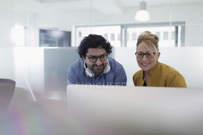 Улыбающиеся деловые люди встречаются за компьютером в офисе — стоковое фото