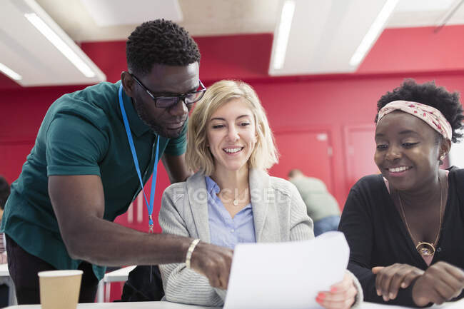 Community college instructor helping students with paperwork in classroom — Stock Photo