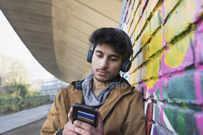 Молодий чоловік з навушниками слухає музику на міському тротуарі — стокове фото