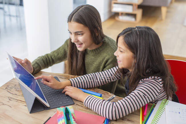 Chicas haciendo la tarea, compartir tableta digital en la mesa - foto de stock