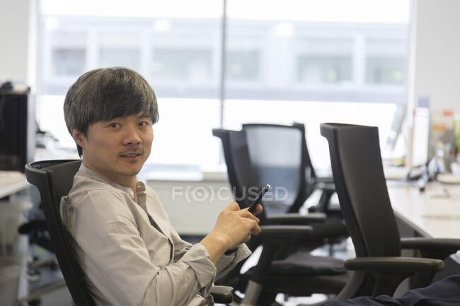 Portrait confident businessman with smart phone in office — Stock Photo