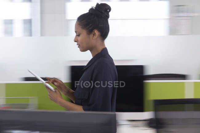 Femme d'affaires avec tablette numérique marche dans le bureau — Photo de stock