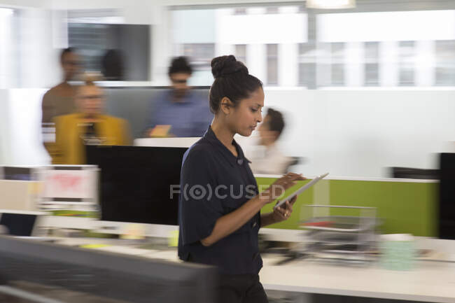 Businesswoman with digital tablet walking in office — Stock Photo