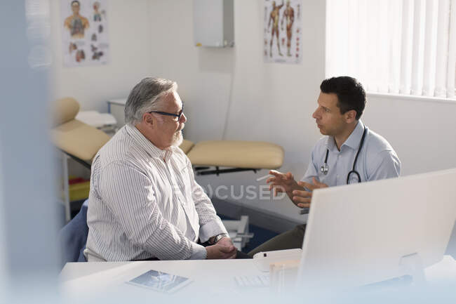 Male doctor talking with patient in doctors office — Stock Photo
