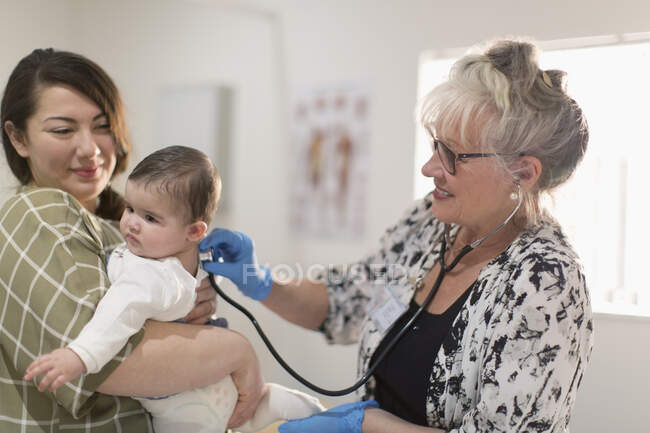 Female pediatrician with stethoscope examining baby girl in examination room — Stock Photo
