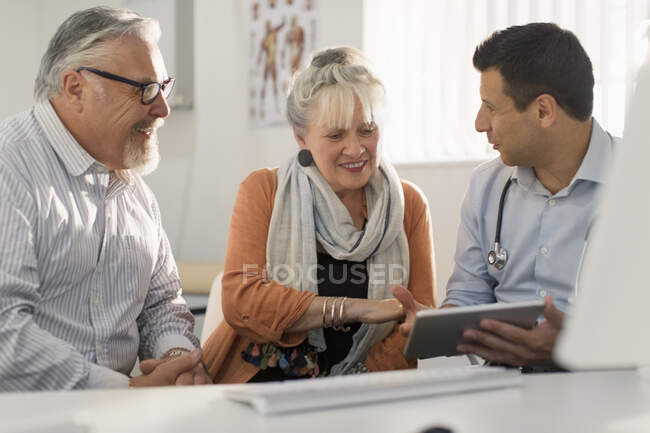 Médico com tablet digital reunião com casal em consultório médico — Fotografia de Stock