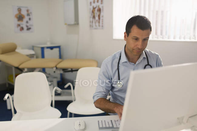 Male doctor working at computer in doctors office — Stock Photo
