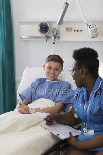 Female nurse talking with boy patient in hospital room — Stock Photo