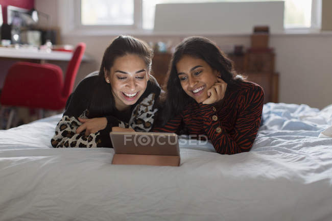 Щасливі дівчата-підлітки використовують цифровий планшет на ліжку — стокове фото