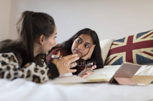 Дівчата-підлітки навчаються, розмовляють на ліжку — стокове фото