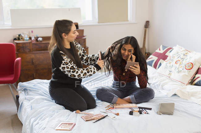 Дівчата-підлітки наносять макіяж і чистять волосся на ліжку — стокове фото