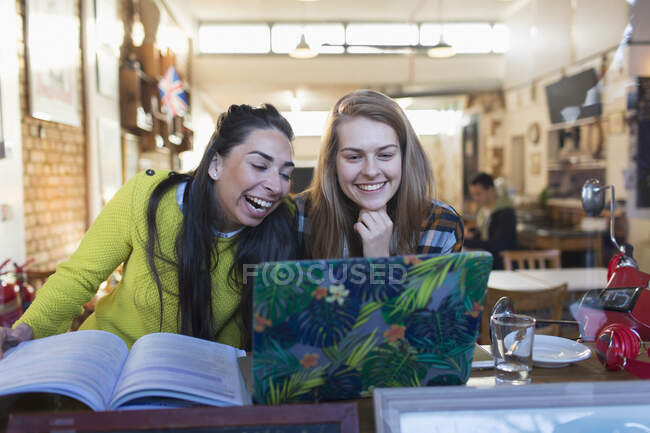 Feliz, rindo jovens estudantes universitárias usando laptop na janela do café — Fotografia de Stock