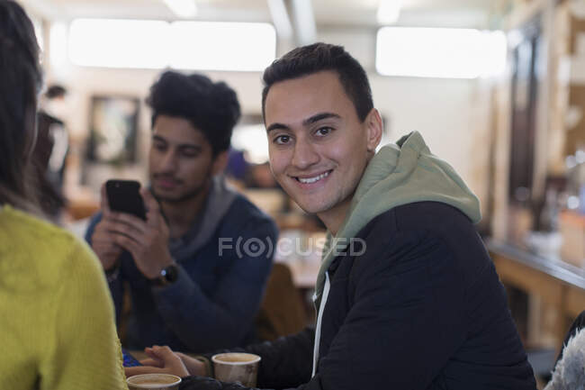 Retrato confiado joven pasar el rato con amigos en la cafetería - foto de stock