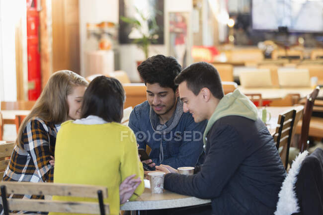 Young friends using smart phones at cafe table — Stock Photo