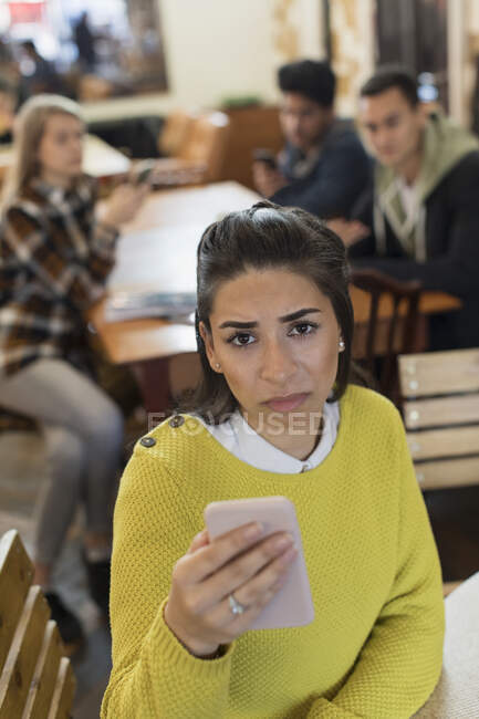 Портрет засмученої молодої жінки зі смартфоном у кафе — стокове фото