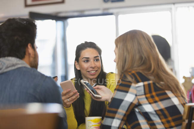Молодые друзья используют смартфоны в кафе — стоковое фото