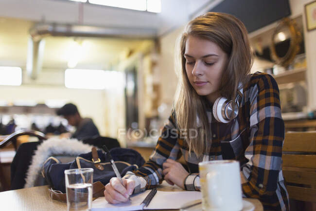 Joven estudiante universitaria estudiando en la cafetería - foto de stock