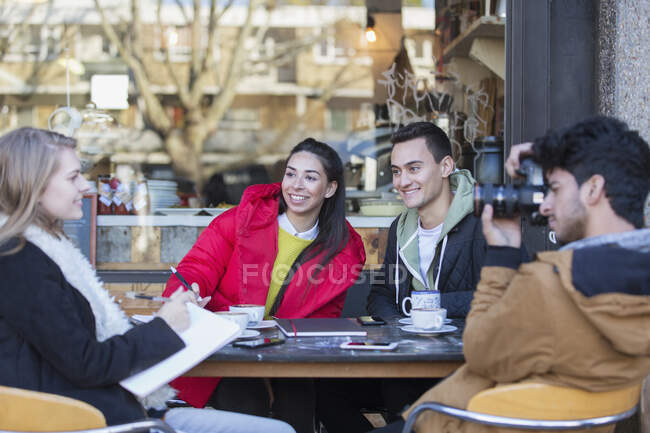 Jovens amigos saindo e estudando no café da calçada — Fotografia de Stock