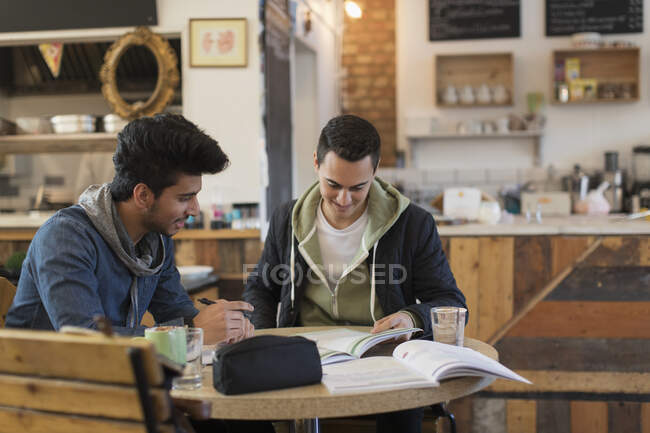 Jóvenes estudiantes universitarios varones estudiando en la cafetería - foto de stock