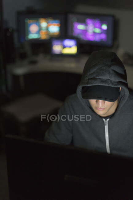 Hacker em capuz no computador no quarto escuro — Fotografia de Stock