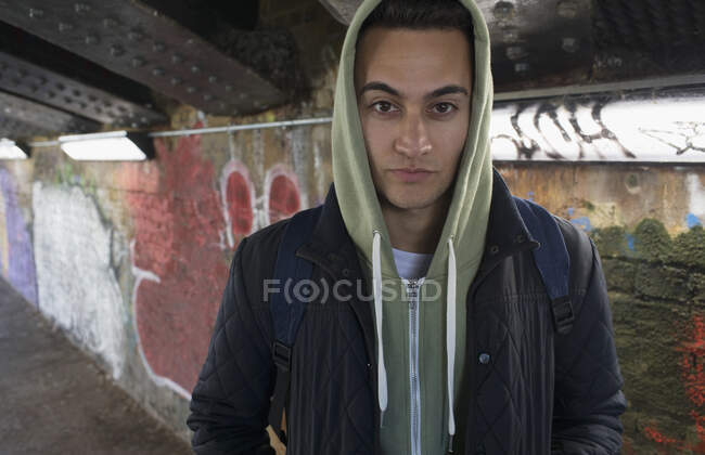 Portrait serious, tough young man wearing hoody in urban tunnel — Stock Photo