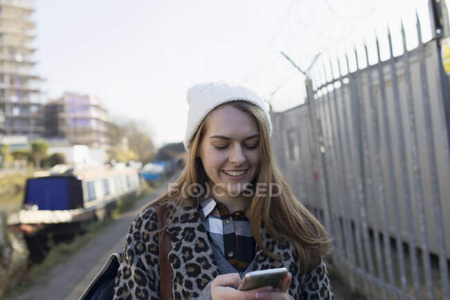Jeune femme utilisant un téléphone intelligent le long du canal — Photo de stock