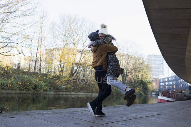 Heureux jeune couple serrant le long du canal urbain — Photo de stock