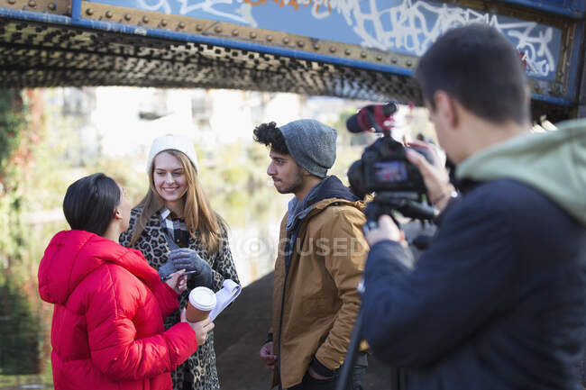 Jóvenes estudiantes de cine filmando bajo puente urbano - foto de stock