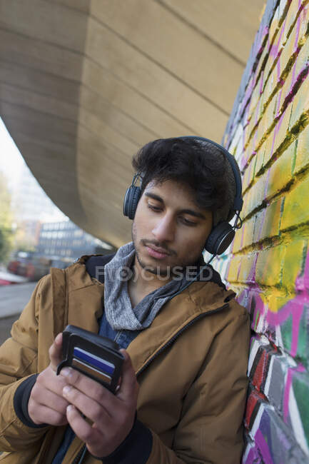 Joven escuchando música con auriculares y reproductor de mp3 - foto de stock