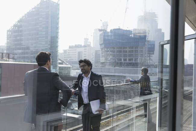 Geschäftsleute unterhalten sich auf sonnigem, urbanem Bürohochhaus-Balkon — Stockfoto